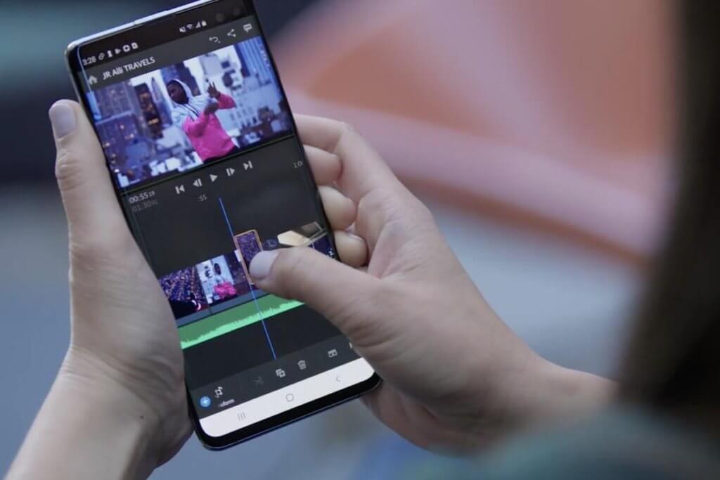 A woman holding a smartphone using Adobe Premiere Rush