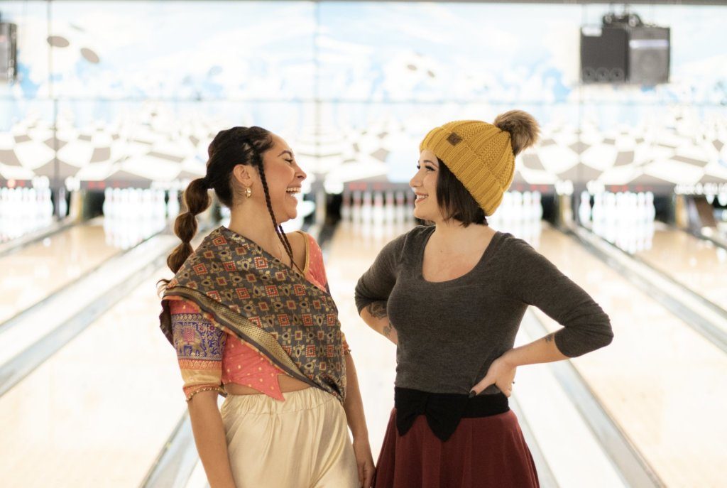Two HelpCloud employees laughing with each other in a bowling alley.