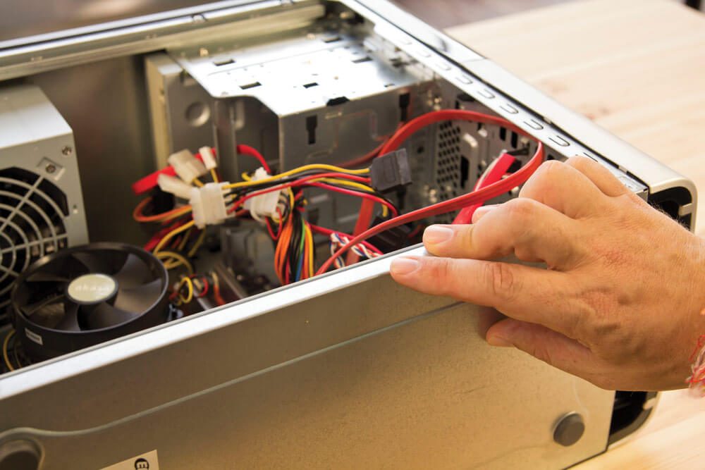 A hand working on an opened computer