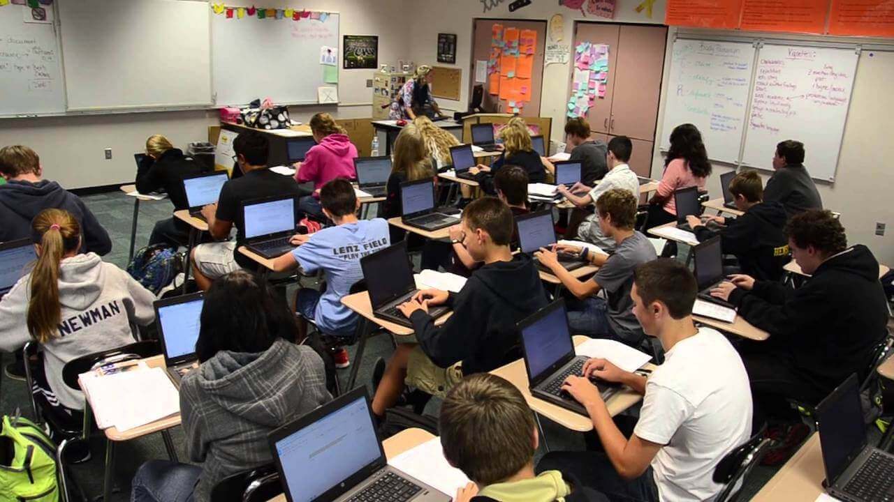 A group of students sitting at their desks on laptops